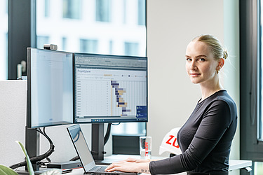 Foto einer kaufmännischen Mitarbeiterin an ihrem Schreibtisch vor dem PC