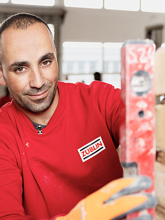 Bild eines Azubis, der mit einer Wasserwaage eine Mauer abmisst.