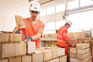 Auszubildender in der Konzernlehrwerkstatt, der gerade Steine aufeinandersetzt.