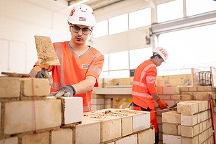 Auszubildender in der Konzernlehrwerkstatt, der gerade Steine aufeinandersetzt.