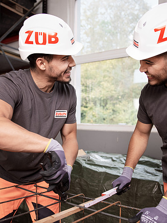 Zwei junge Männer mit Bauhelm, unterhalten sich.