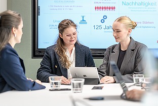 Zwei junge Kolleginnen schauen zusammen in ein Tablet