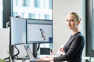 Foto einer kaufmännischen Mitarbeiterin an ihrem Schreibtisch vor dem PC