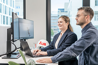 Zwei Kolleg:innen schauen gemeinsam in einen Computerbildschirm