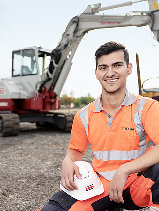 Nahaufnahme einer Mitarbeiterin mit Arbeitsschutzkleidung, lächelt in die Kamera.