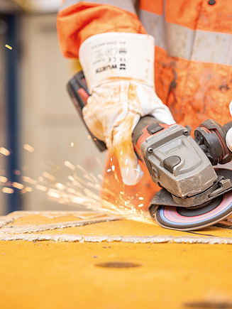 Fotos eines Azubis, der gerade per Fernsteuerungsgerät eine Maschine bedient.