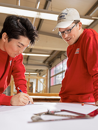 Drei junge Männer, von der Seite abgebildet blicken in dieselbe Richtung.