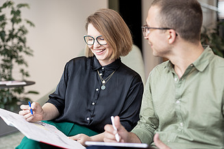 Foto von zwei Auszubildenden, die ihre Notizbücher in der Hand halten und miteinander sprechen
