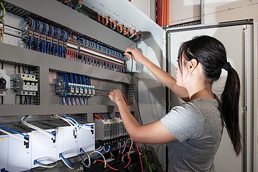 Eine junge Frau arbeitet an einer technischen Anlage.