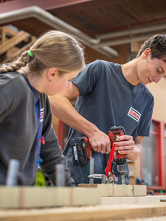 Foto eines Azubis, der gerade an einer Holzkonstruktion arbeitet.