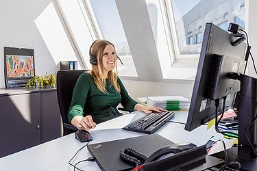 Foto einer kaufmännischen Mitarbeiterin an ihrem Schreibtisch vor dem PC