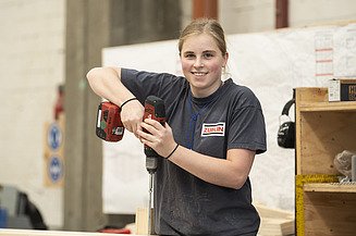 Ausbildung Zimmerer:Zimmerin Foto einer Auszubildenden, die eine Bohrmaschine in der Hand hält.