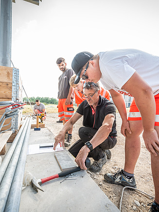 Foto eines Ausbilders und ein paar Azubis, die etwas erklärt bekommen