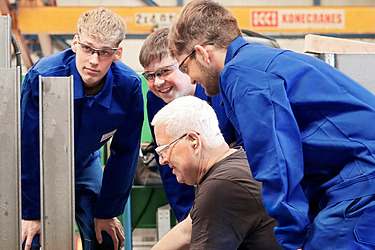 Bild auf dem ein Ausbilder drei Azubis etwas erklärt.