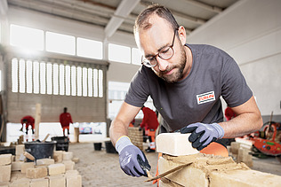 Auszubildender in der Konzernlehrwerkstatt, der gerade Steine aufeinandersetzt.