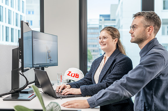 Frau mit Mann stehen vor einem PC
