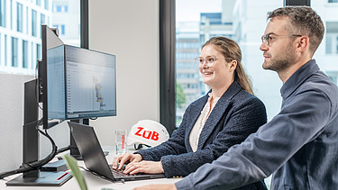 Zwei Kolleg:innen schauen gemeinsam in einen Computerbildschirm
